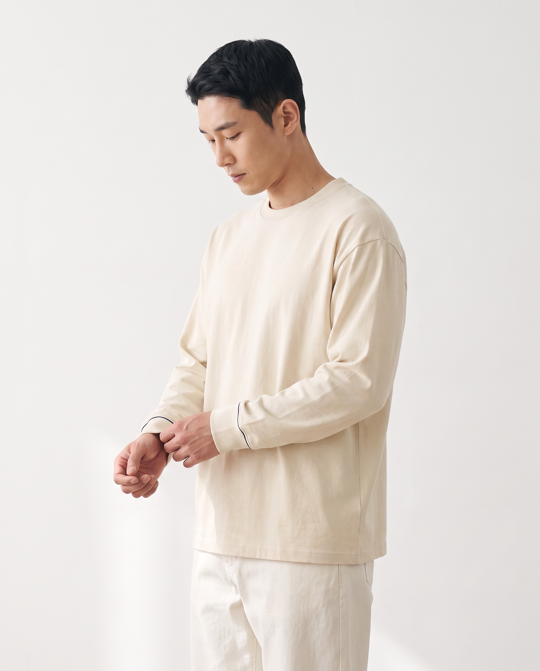The Heavy Long Sleeve in milk apricot, side view, adjusting the cuff