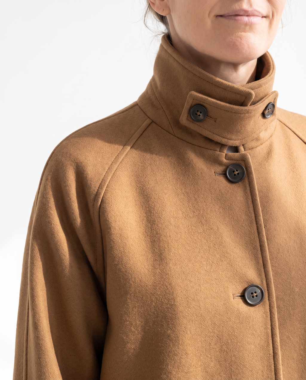 The Coat, convertible collar worn up and fastened by its tab button